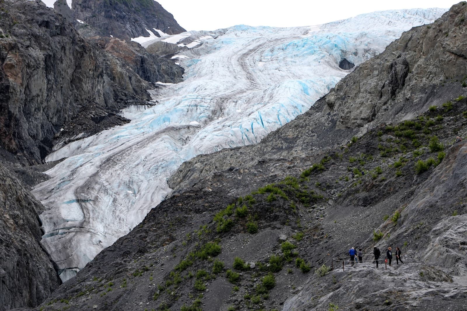 Hikers on an overlook above the crevassed blue ice of Exit Glacier in Kenai Fjords National Park